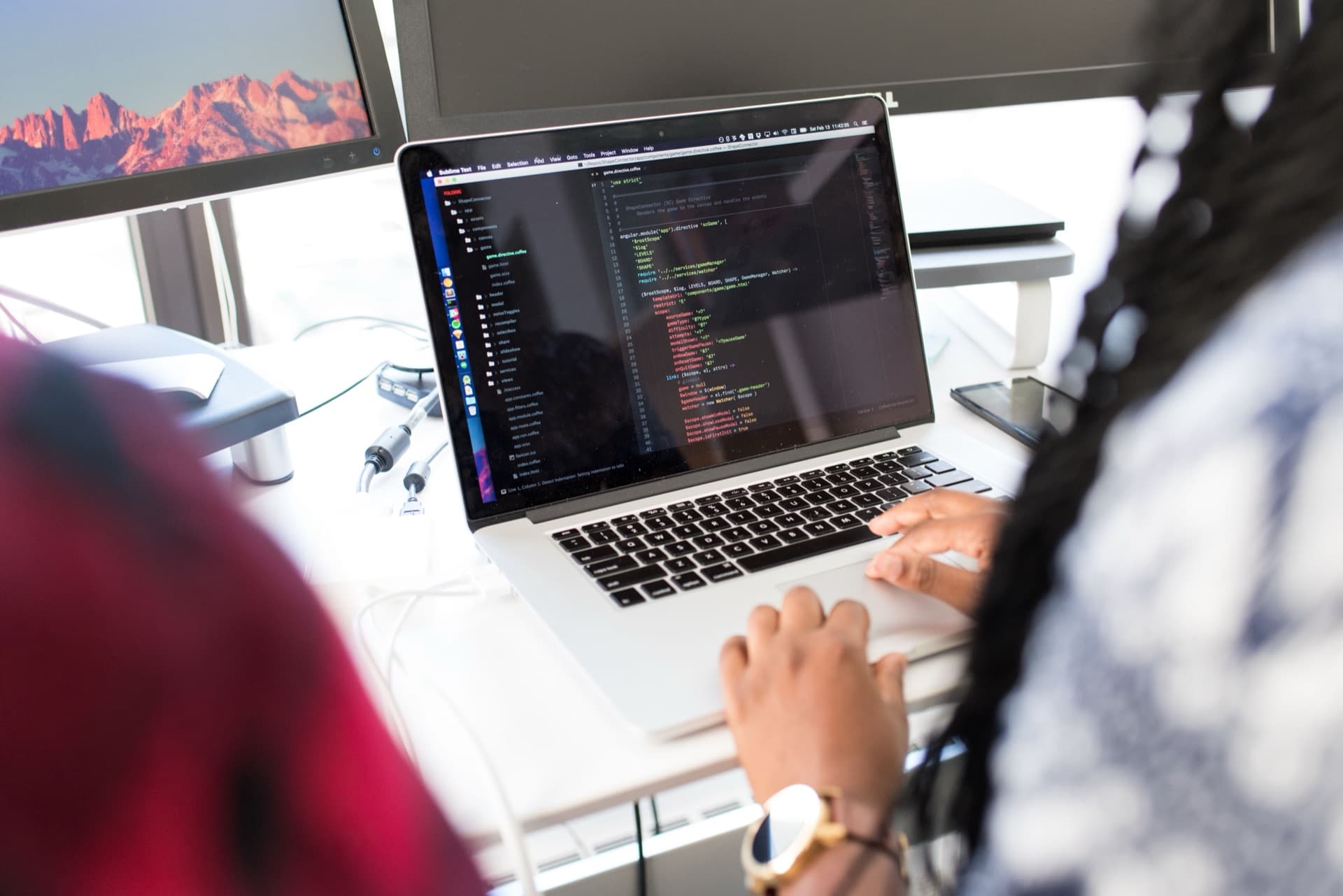 IT professional configuring software on a laptop with dual monitors